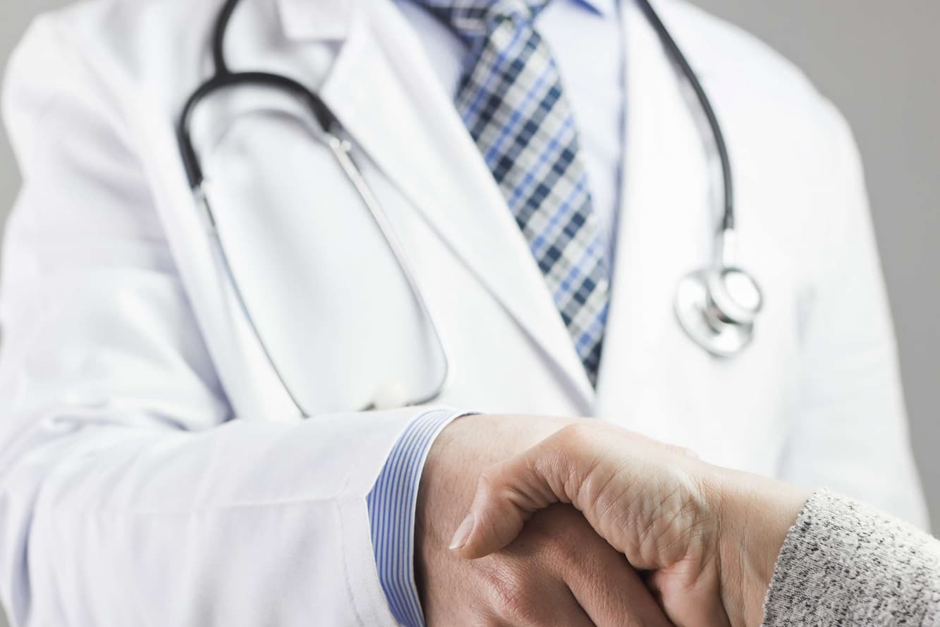 close up male doctor shaking hand with patient against gray background 1 2